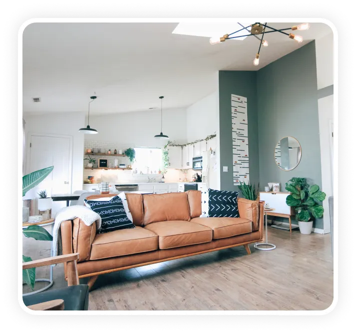 Living comedor luminoso con sillón de cuero, plantas y cocina integrada